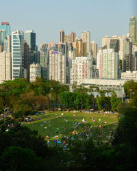 Trees and buildings in city against sky