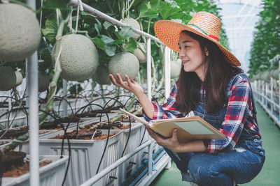 Woman standing by plants at greenhouse