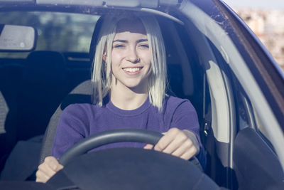 Portrait of smiling woman driving car seen through windshield