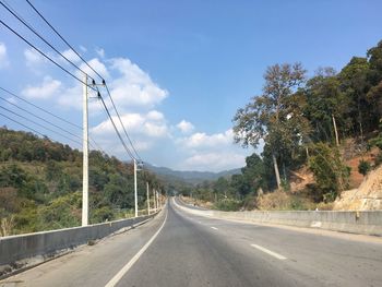 Road by trees against sky