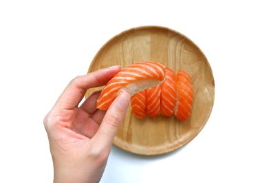 Close-up of hand holding orange over white background