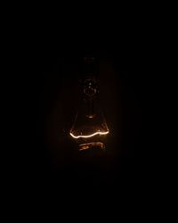 Close-up of illuminated light bulb against black background