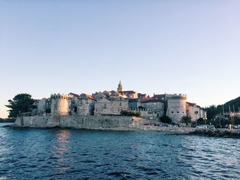 River in front of town against clear blue sky