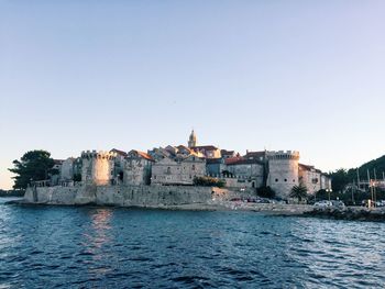 Buildings in old town by sea against clear sky