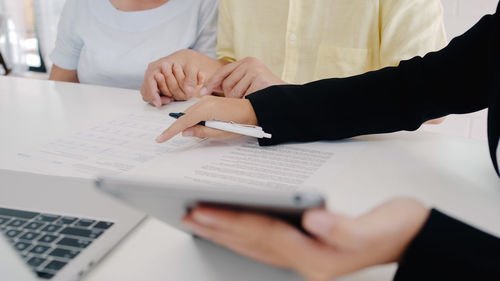 Midsection of man and woman using mobile phone on table