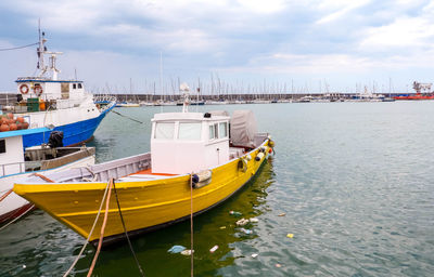 Boats moored at harbor against sky