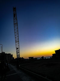 Silhouette cranes against sky during sunset