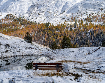 Snow covered field by trees against mountain