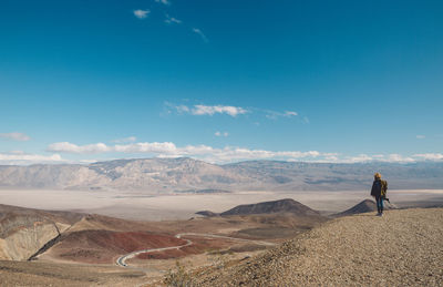 View of woman standing on desert against blue sky