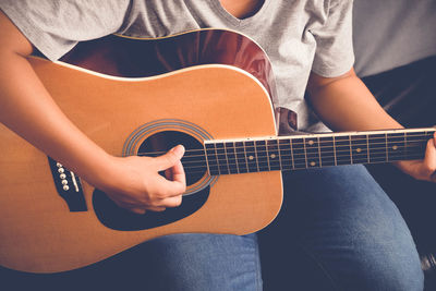 Midsection of woman playing guitar