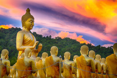 Buddha statue against sky at sunset