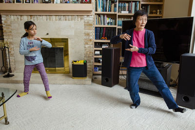 Asian grandmother teaching granddaughter taichi at home