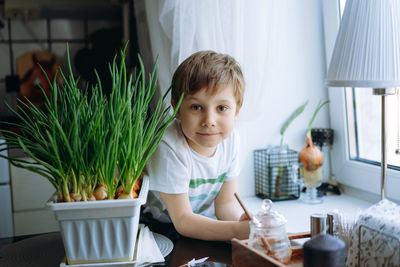 Little boy care of planted fresh onion.