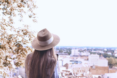 Rear view of woman looking at cityscape against sky