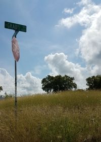 Low angle view of road sign on field against sky