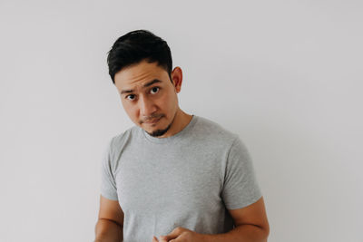 Portrait of young man standing against white background