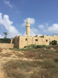 Buildings on field against cloudy sky