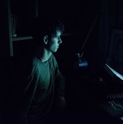Young man looking into computer in room at home