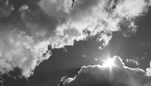 Low angle view of sunlight streaming through clouds