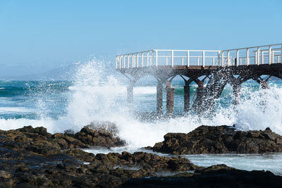 Waves splashing in sea against clear sky