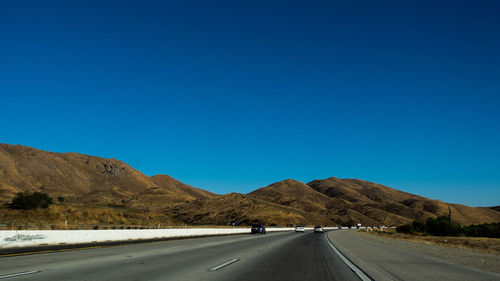 Road by mountain against blue sky