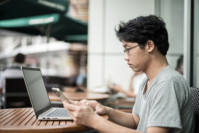 Side view of young man using mobile phone