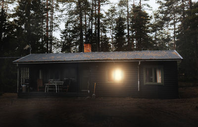 Exterior of log cabin with trees in background at sunset