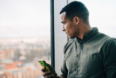 Side view of young man using mobile phone in city