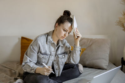 Young beautiful woman with casual clothes sitting on the bed at home with laptop computer 