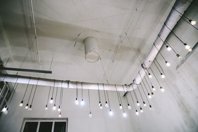 Low angle view of illuminated lights hanging on ceiling in building