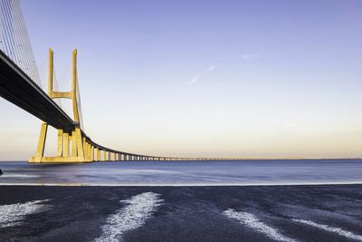 Bridge over sea against sky during sunset