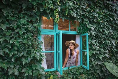 Woman standing against door of plants