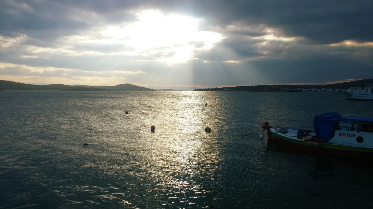 water, sky, cloud - sky, nautical vessel, transportation, mode of transport, sun, sea, boat, scenics, cloudy, reflection, sunbeam, tranquility, tranquil scene, sunlight, beauty in nature, nature, cloud, moored