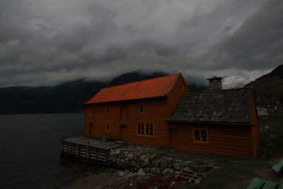 Houses by mountain against sky at dusk