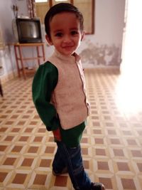 Portrait of cute boy standing on floor at home