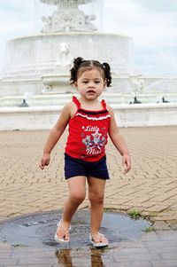 Full length of girl playing in puddle on footpath