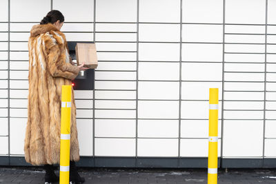 Rear view of woman standing against wall