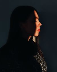 Portrait of a young woman looking away over black background