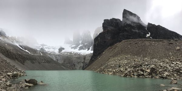 Scenic view of lake by snowcapped mountains against sky