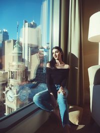 Thoughtful woman sitting on window sill