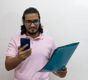 Young man using mobile phone against white background