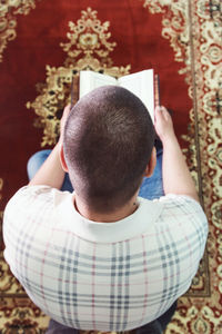 Directly above shot of man reading koran in mosque
