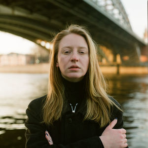 A woman stands at sunset near the bridge