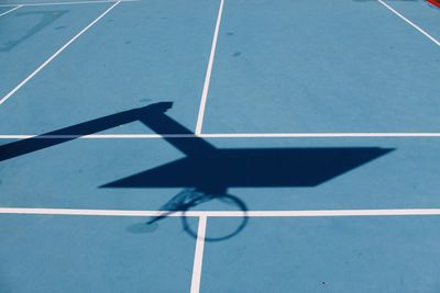 High angle view of basketball hoop shadow pn blue court