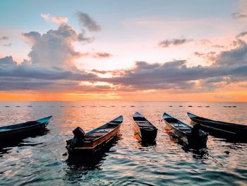 Boat moored on sea against sky during sunset