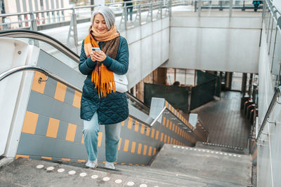 Low angle view of young woman standing on escalator