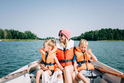 Friends sitting on boat against sky