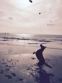 Silhouette man on beach against sky during sunset