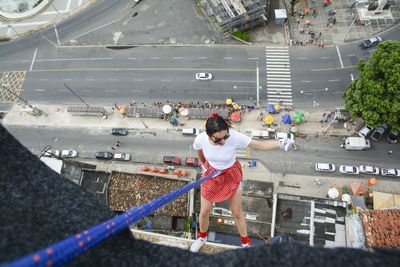 Caucasian woman wearing hero costume descending a tall building in rappel. salvador bahia brazil.