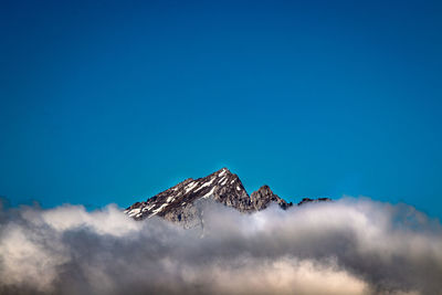 Low angle view of snowcapped mountain against blue sky